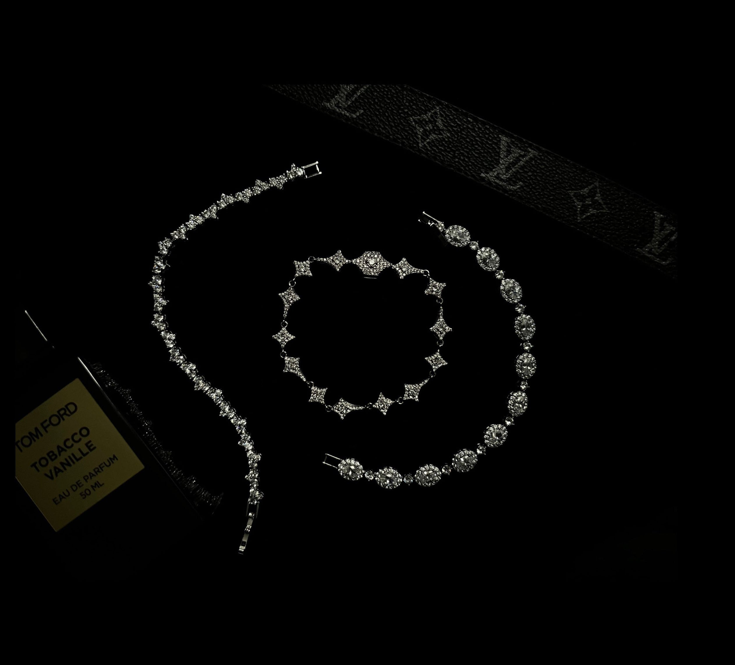 Diamond jewelry set on a dark surface with a visible brand logo.
